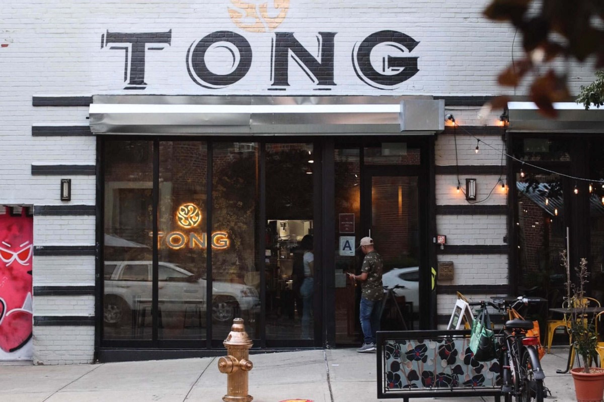 Exterior storefront of Tong restaurant with sign, large windows, and string lights