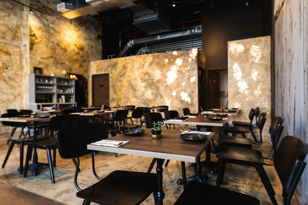 Interior dining room of Tong with wooden tables, black chairs, and textured walls