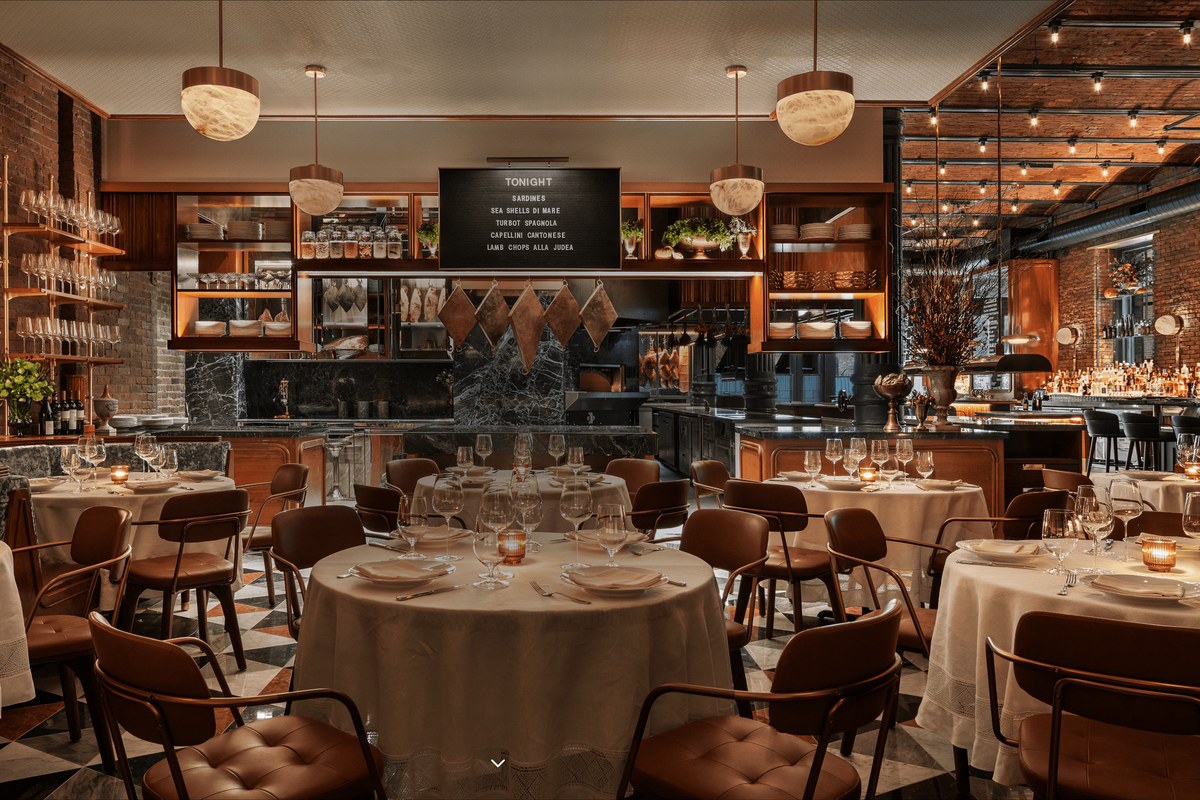 Torrisi dining room with round tables set for service, open kitchen and marble counters