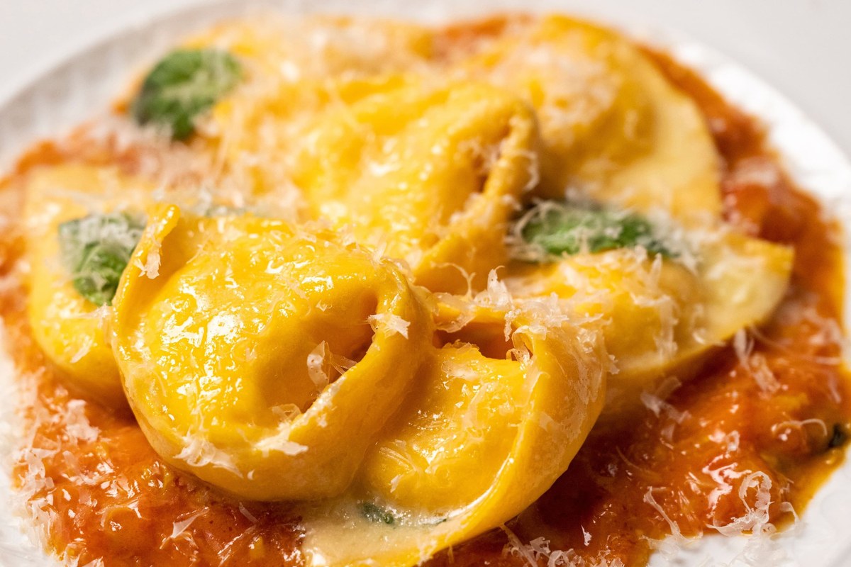 Close-up of a pasta dish - golden filled pasta in tomato sauce with grated cheese