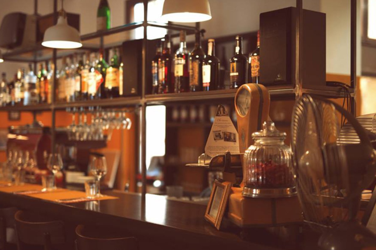 Bar counter with shelves of bottles, glasses, and vintage decor items