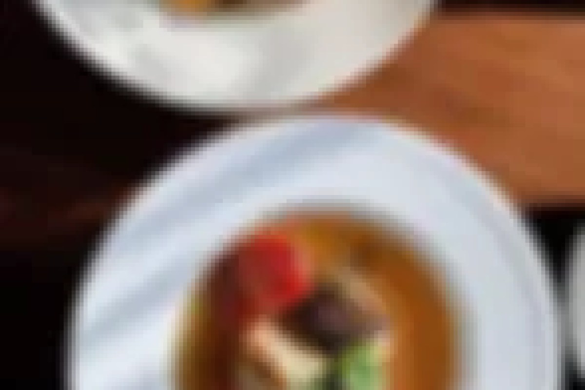 Close-up of a plated dish on a white plate at Untable, with another plate blurred in background