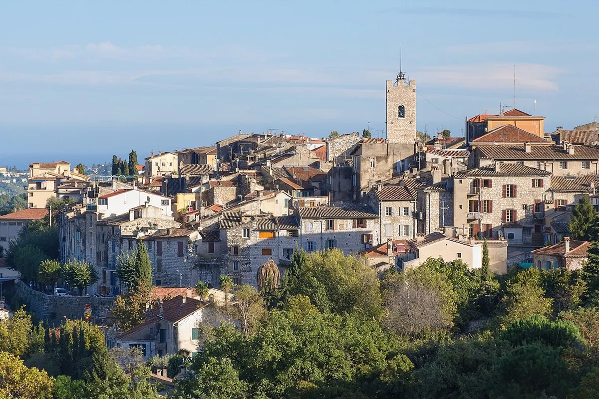 The old town of Vence with its bell tower rising above stone houses and greenery