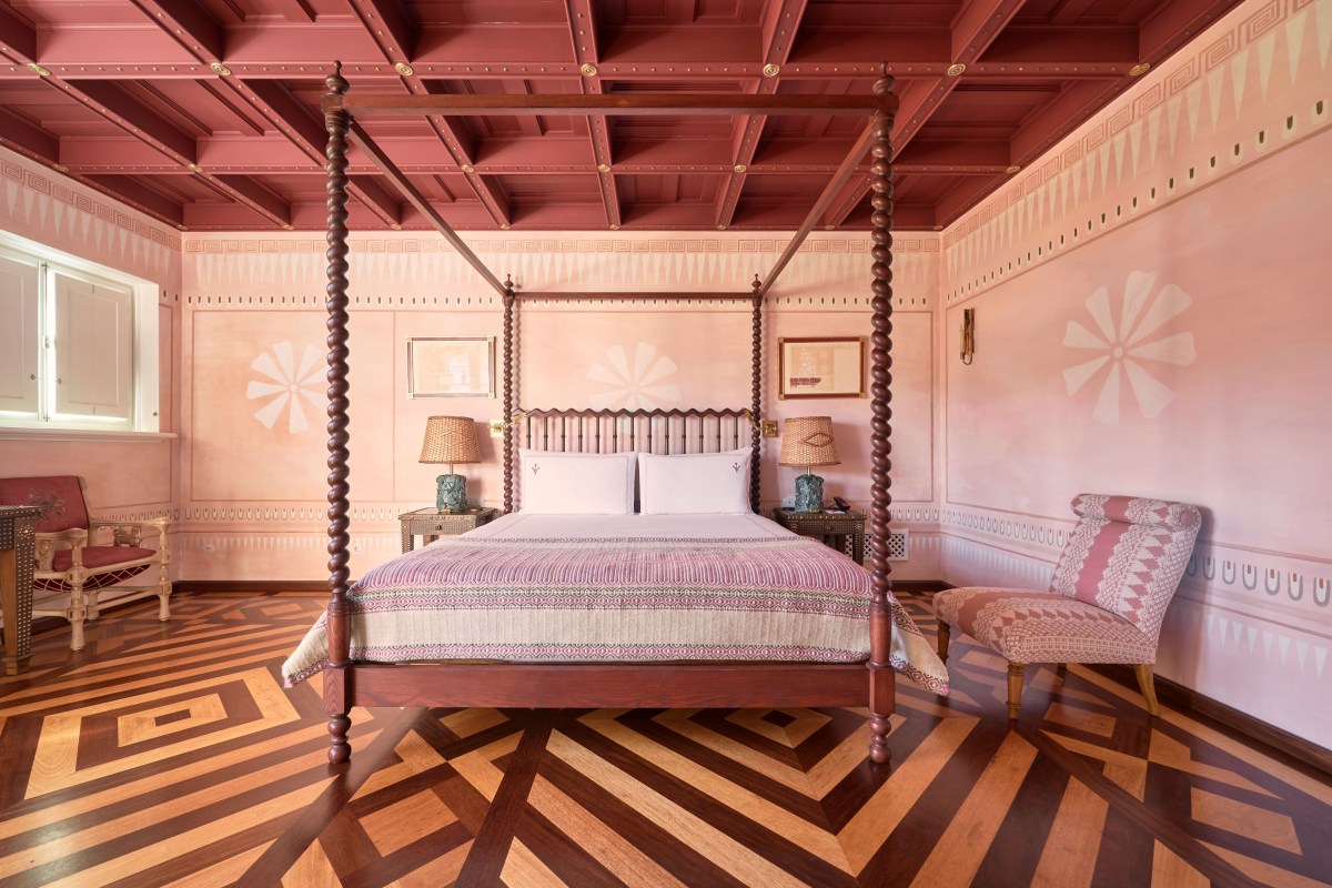Pink-themed guest room with four-poster bed and patterned wood floor