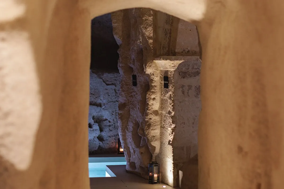 Cave-style corridor with lanterns leading to an illuminated indoor pool