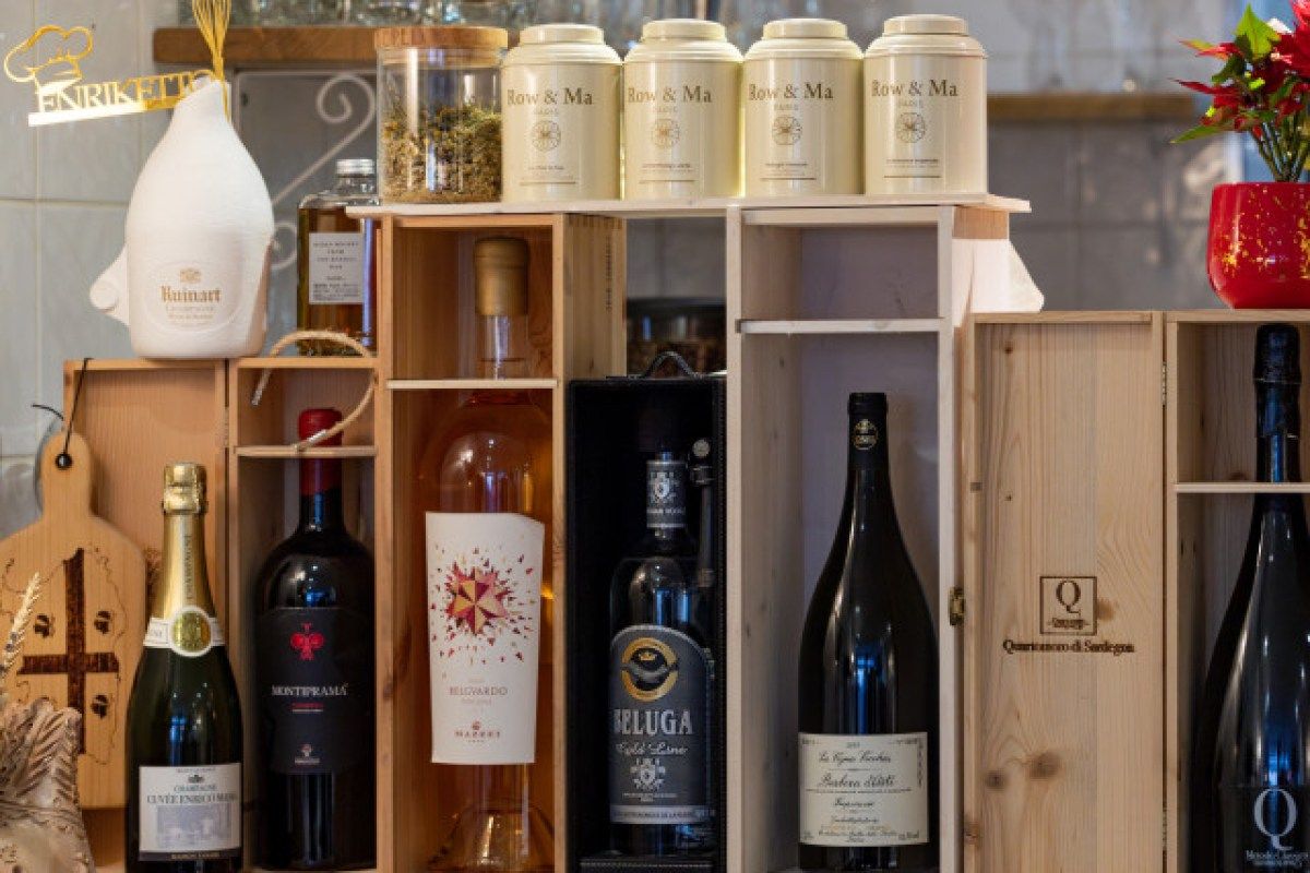 Shelved display of wine and liquor bottles with tea tins on a bar counter