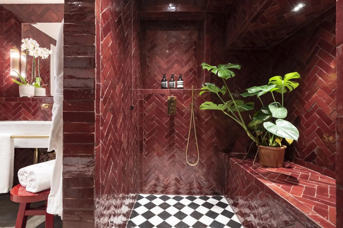 En-suite bathroom with deep red herringbone tile shower, checkerboard floor, and potted plant