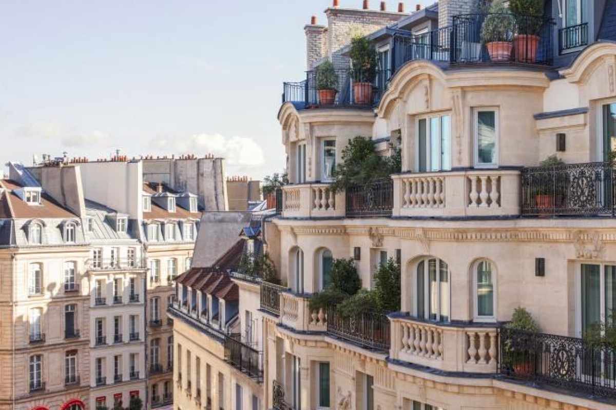 Haussmann-style Paris building facade with balconies and rooftop plants, exterior view