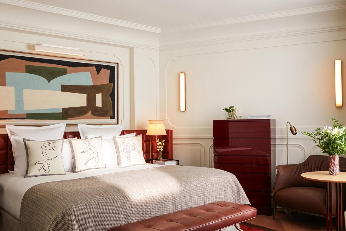 Hotel bedroom with red leather headboard, abstract art, and red dresser