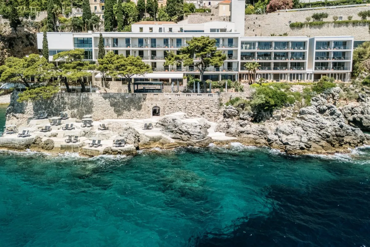 Villa Dubrovnik, white terraced hotel building on a pine-covered cliff above the turquoise Adriatic and its own beach