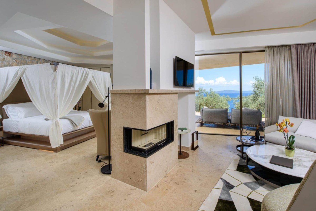 Spacious suite with canopy bed, fireplace, living area, and sea-view terrace