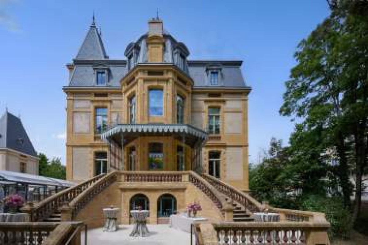 Villa Pétrusse's ornate exterior facade with twin staircases and turret under a blue sky