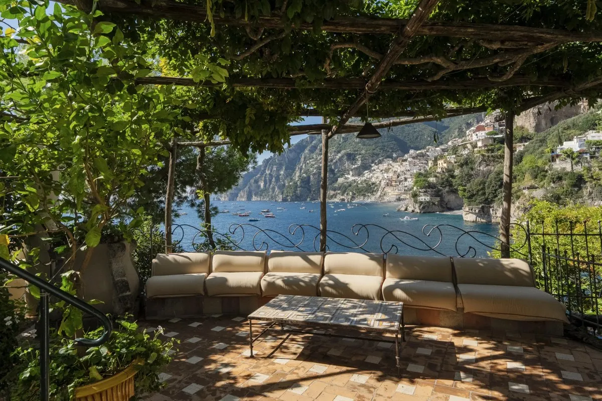 Pergola-covered terrace lounge seating with panoramic view of Positano and the sea