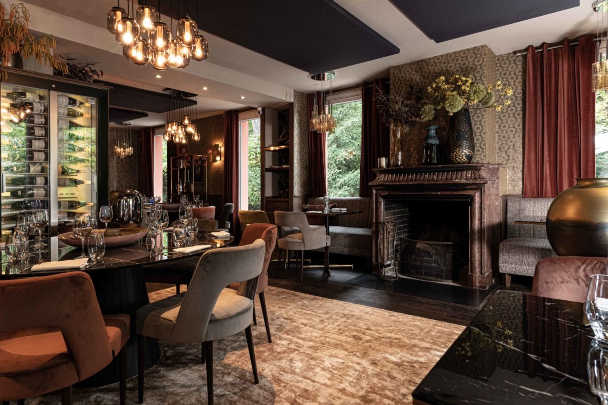 Cozy dining room interior with fireplace, chandeliers, and richly upholstered seating