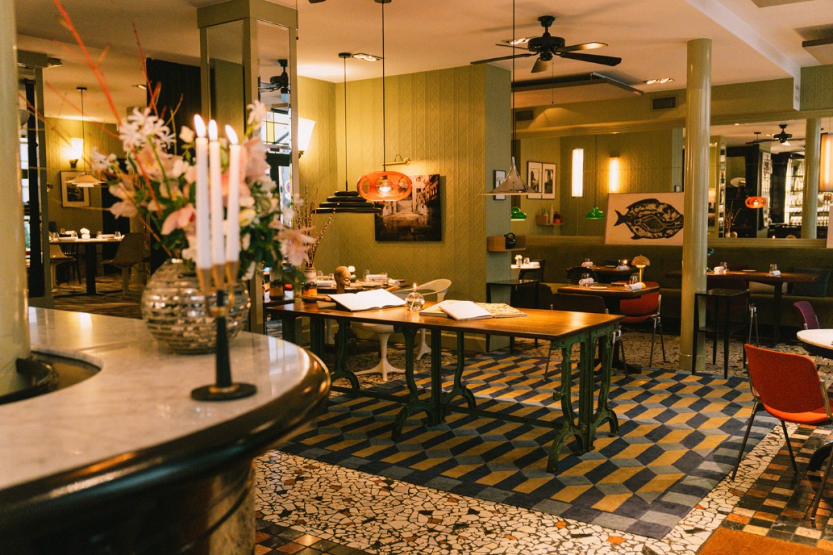 Colorful dining room with terrazzo floor, green walls, pendant lamps and set tables