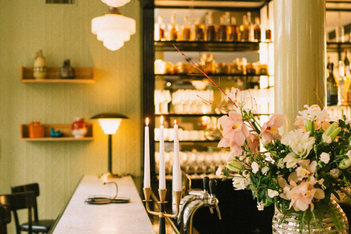 Bar area with marble counter, candles, flowers and bottle-lined mirrored shelves