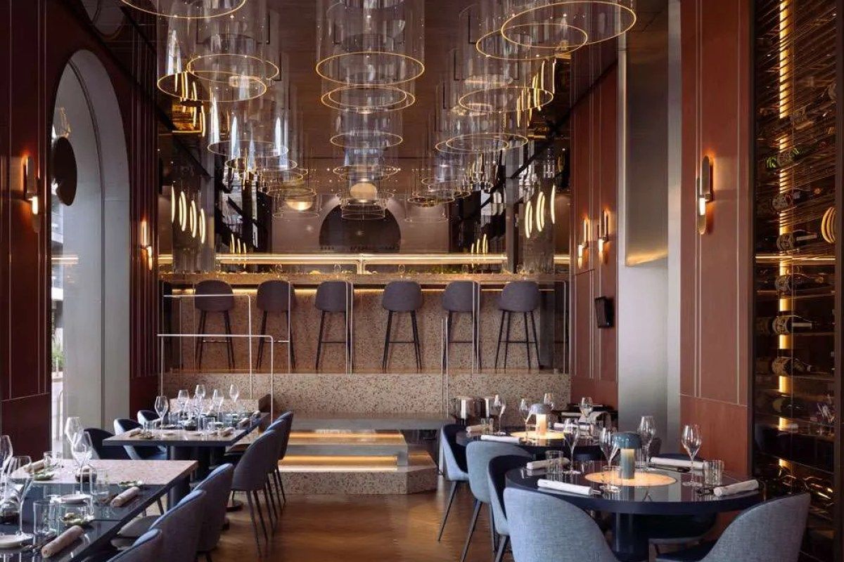 Elegant restaurant dining room with bar, stools, pendant lighting and wine display