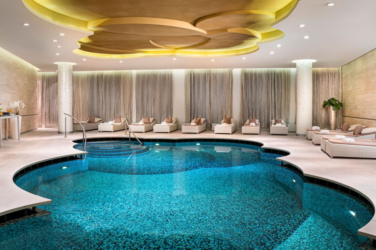 Indoor hotel pool with mosaic tile, lounge chairs and decorative ceiling