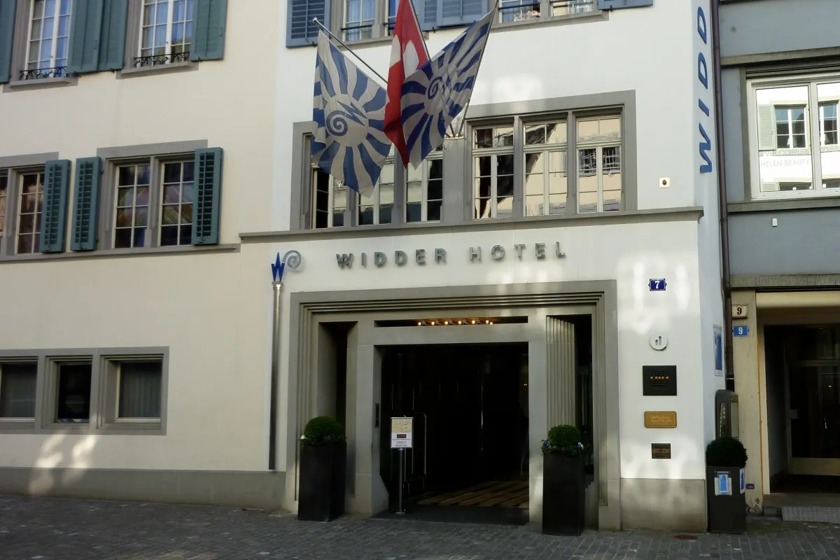 Facade and entrance of Widder Hotel in Zurich with flags and shuttered windows