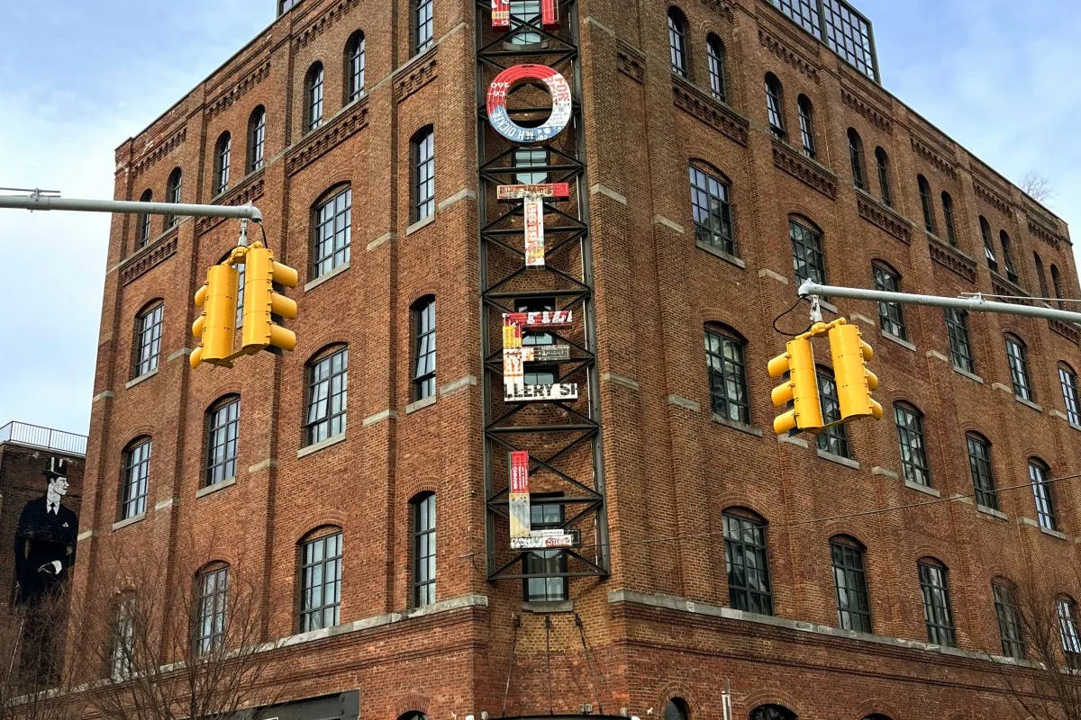 Brick facade of Wythe Hotel with rooftop sign and traffic lights in foreground