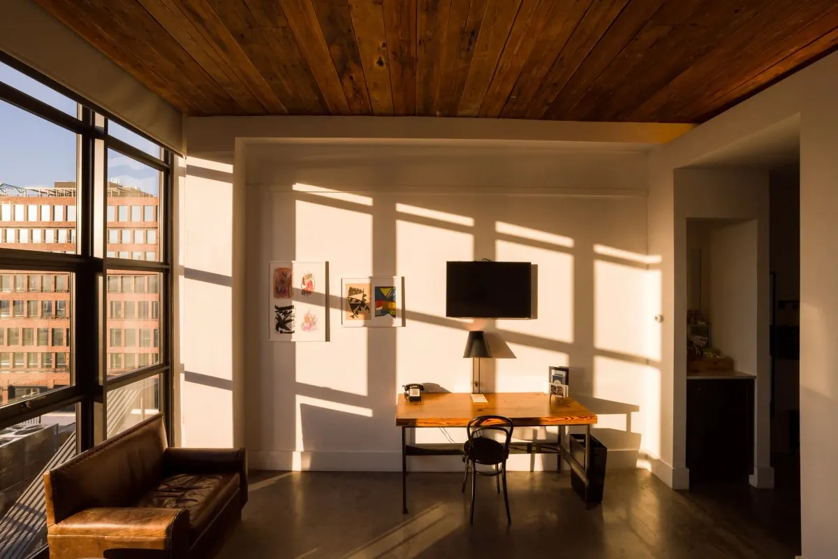 Guest room with wood ceiling, desk, leather sofa and city view windows