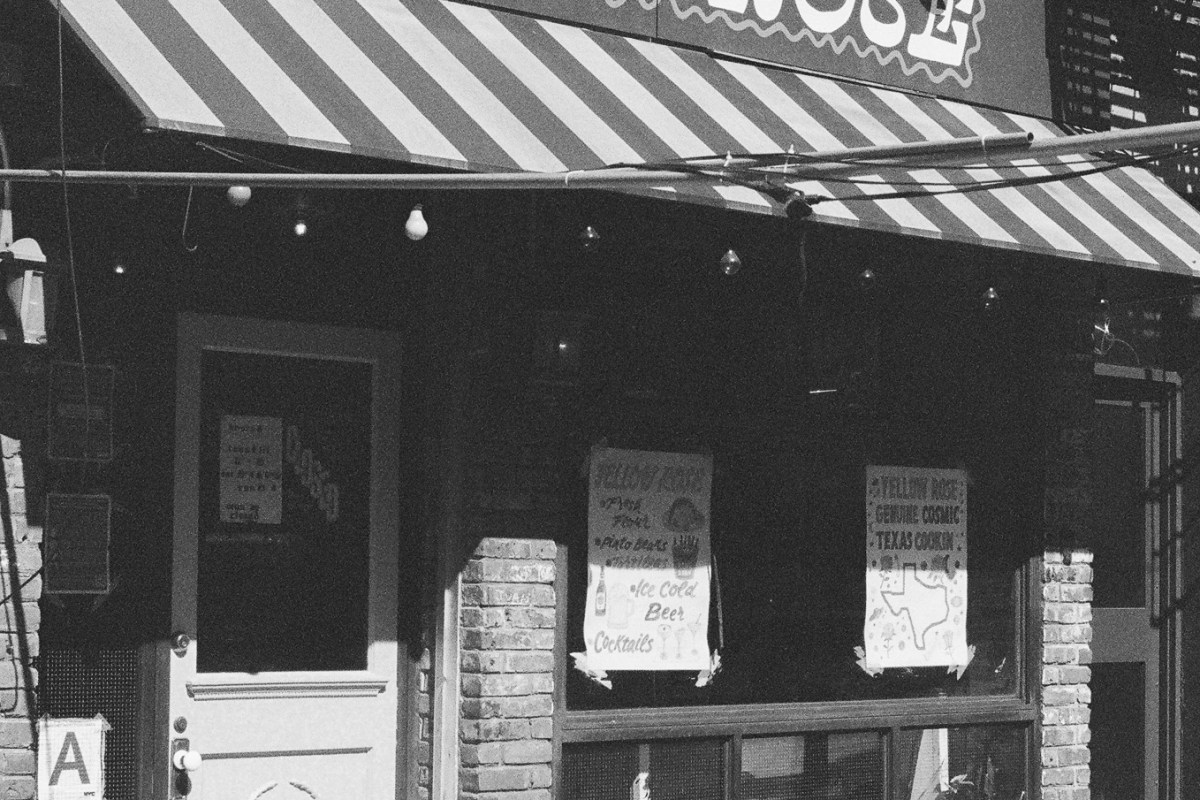 Black and white photo of Yellow Rose restaurant exterior with striped awning and menu signs in window