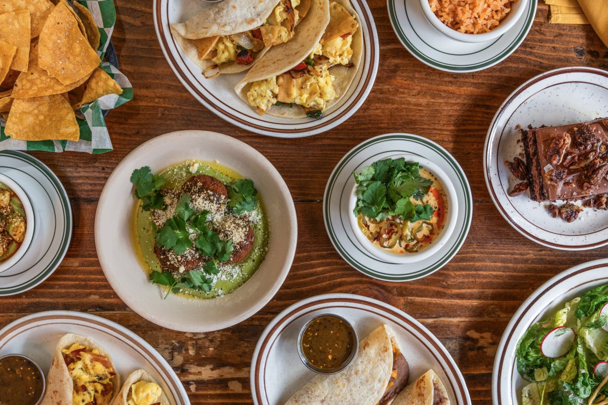 Overhead spread of Yellow Rose dishes including tacos, chips, salad, and chocolate cake