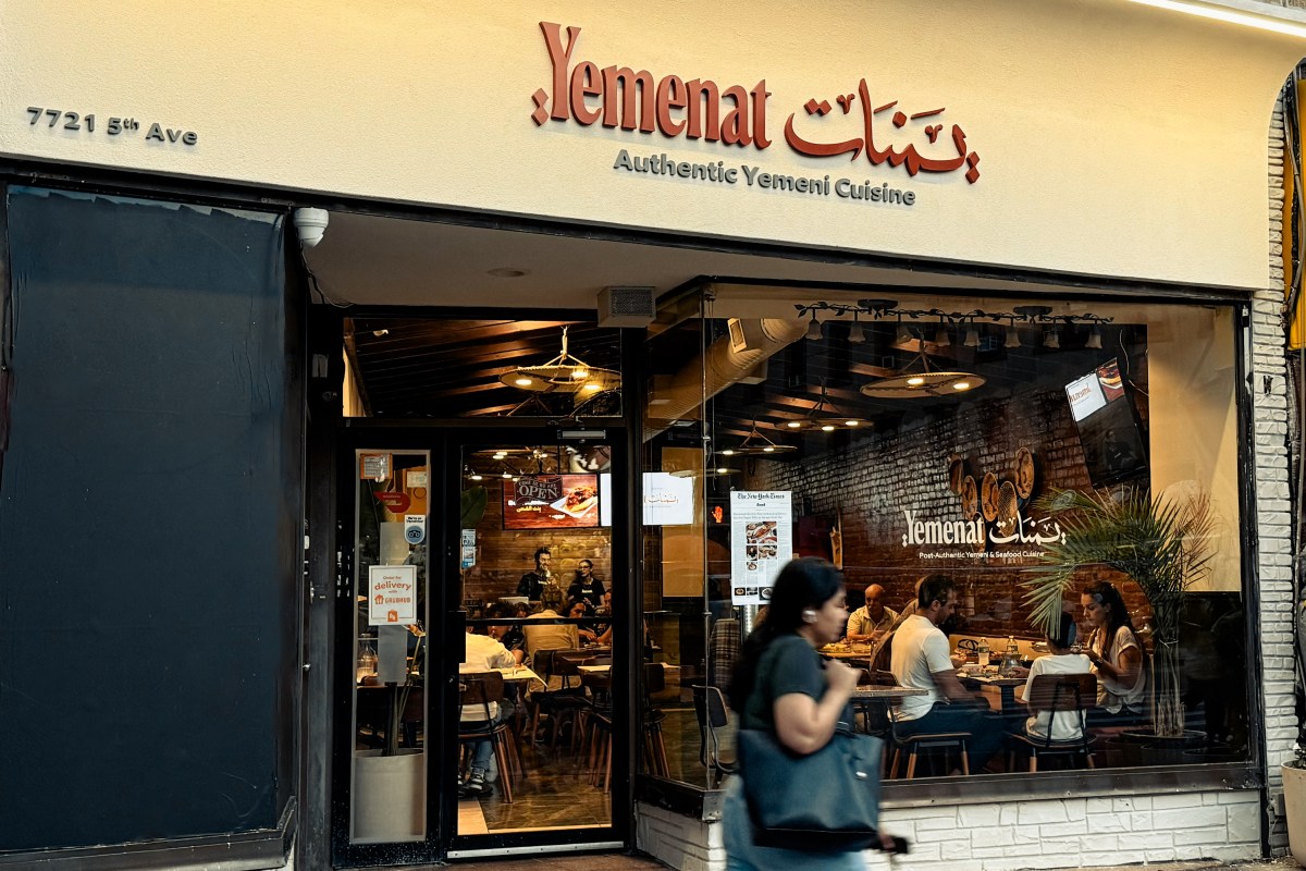 Exterior storefront of Yemenat restaurant with sign, glass facade showing dining room and diners inside, pedestrian walking past