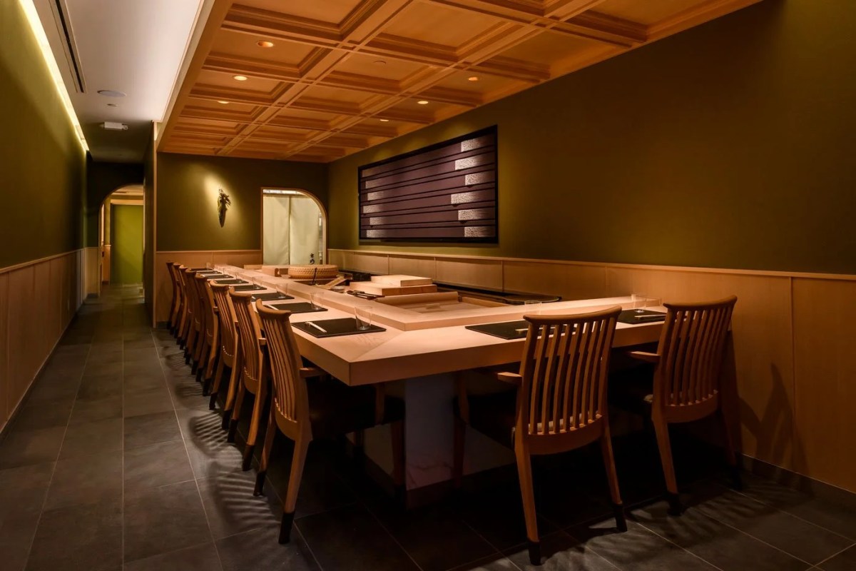 Dining room with long wooden communal table, chairs, and warm wood ceiling