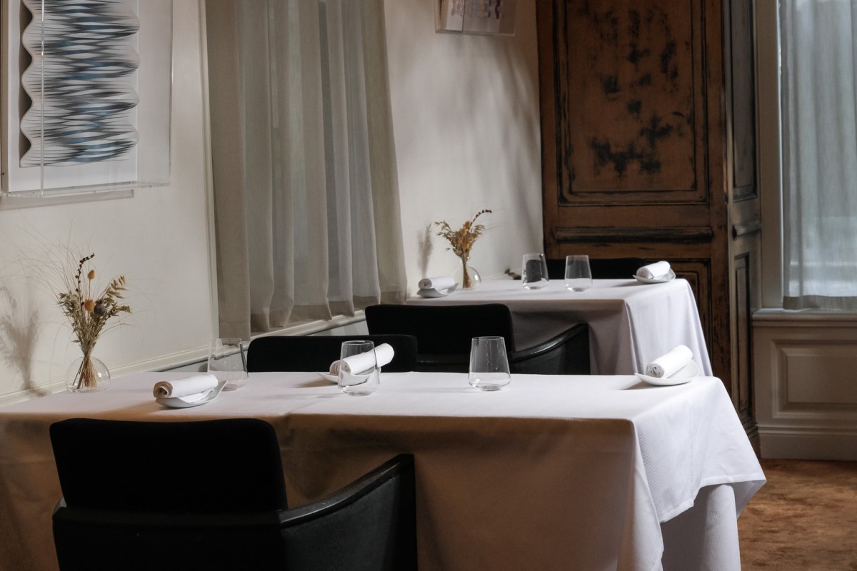 Dining room with two elegantly set tables, black chairs, dried flowers and wall art