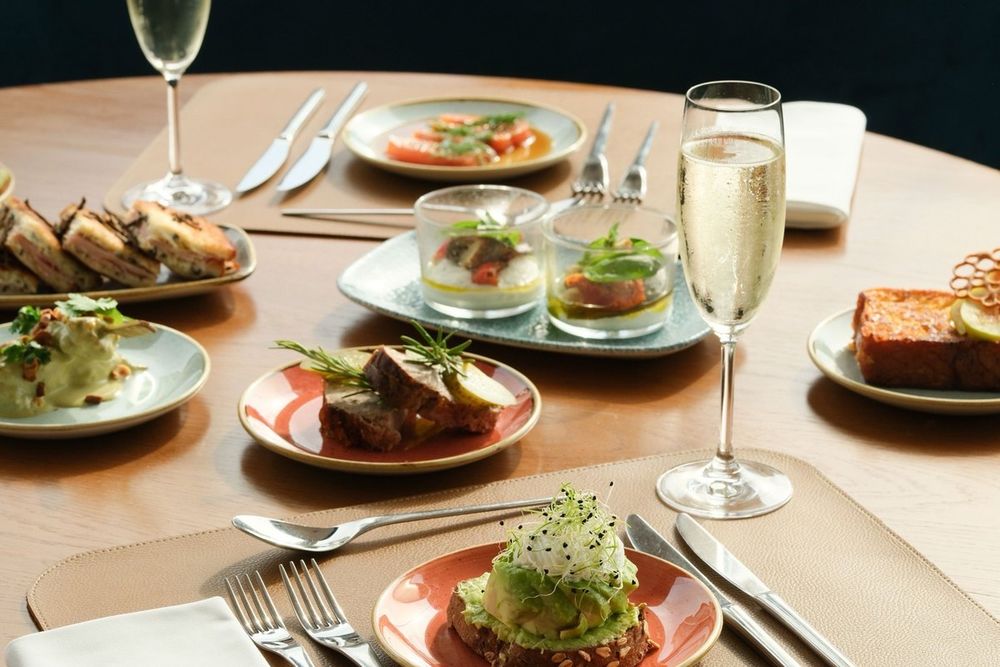 Plates to share and glasses of champagne on a table at Le Roof, Five Seas Hotel, Cannes