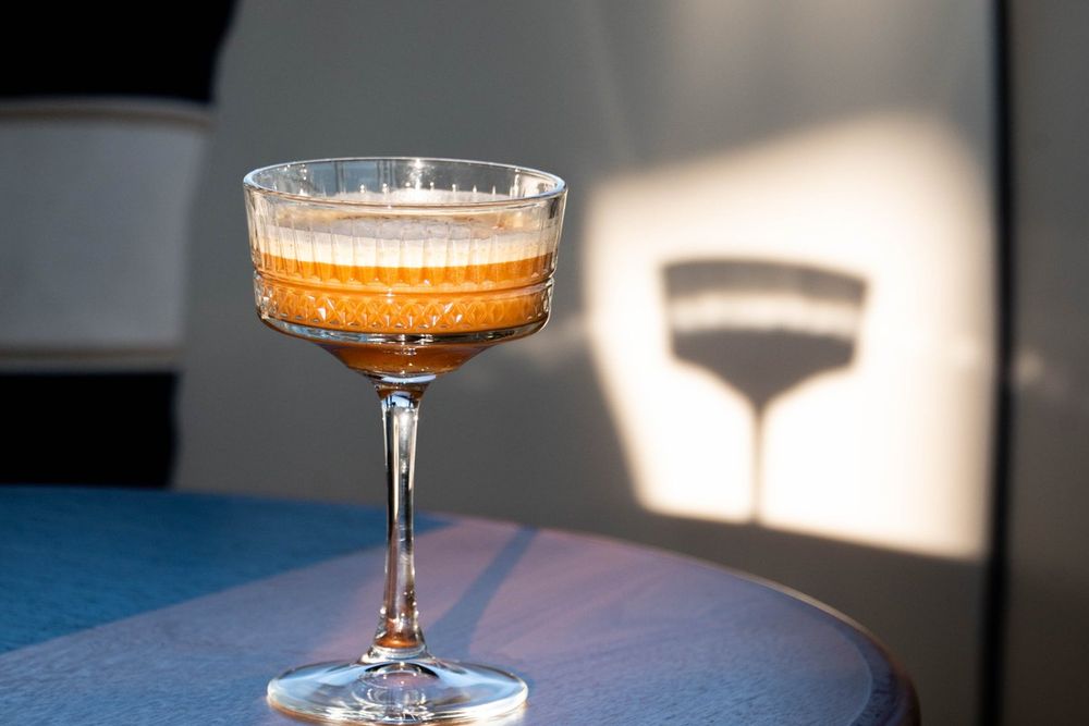 A signature cocktail in a coupe glass catching the evening light at Marea, Cannes