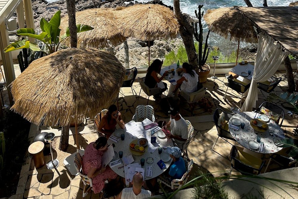 Diners under straw parasols on the terrace of La Pinède, set among pines on the Cap-d'Ail coastal path