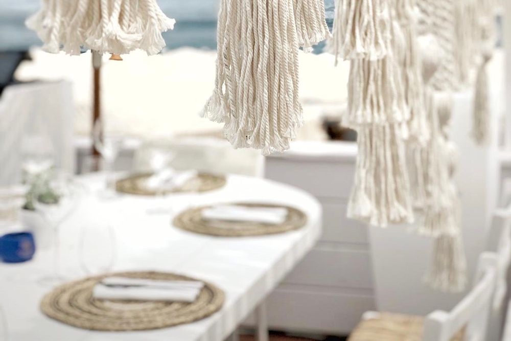White tables under macramé parasols at Naos Beach on Plage Marquet, Cap-d'Ail