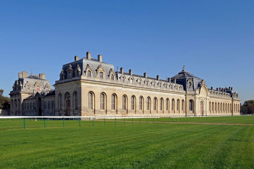 The long façade of the Grandes Écuries across the turf of the Chantilly racecourse