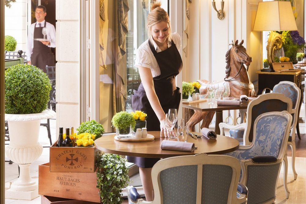 A waitress laying a table in Le Jardin d'Hiver at the Auberge du Jeu de Paume