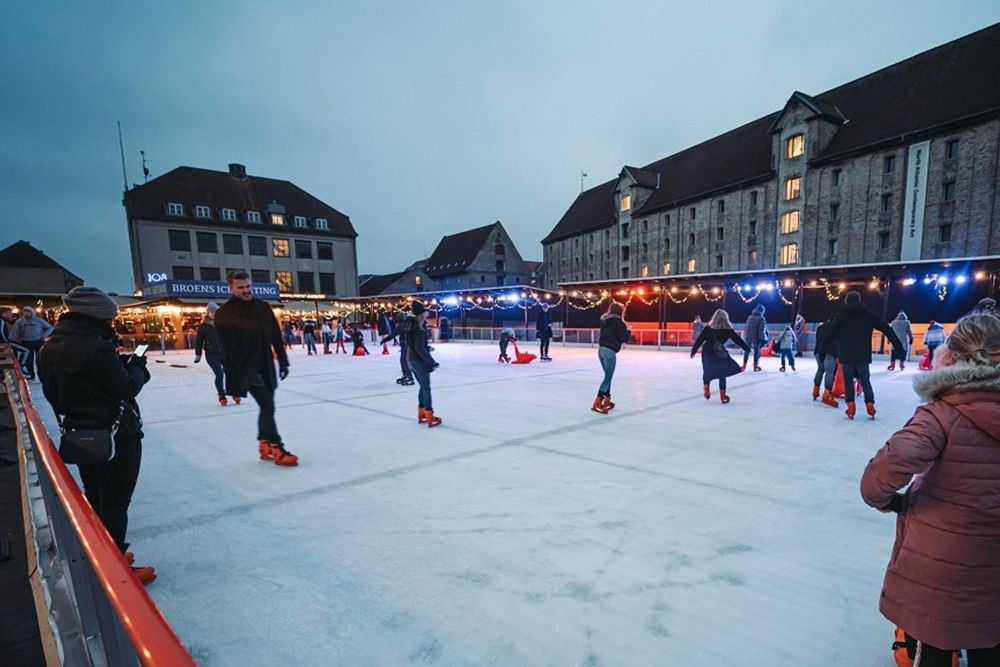 Skaters circling Broens ice rink at dusk beside the old harbour warehouses of Christianshavn