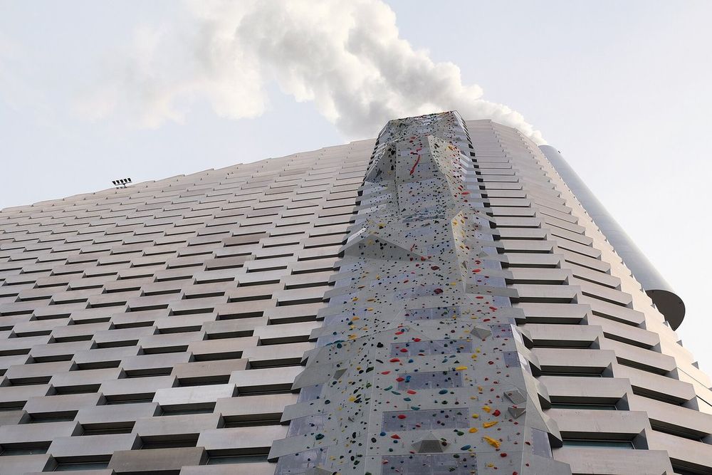 The 85-metre climbing wall running up the sloping, ridged façade of CopenHill, with steam rising from the chimney