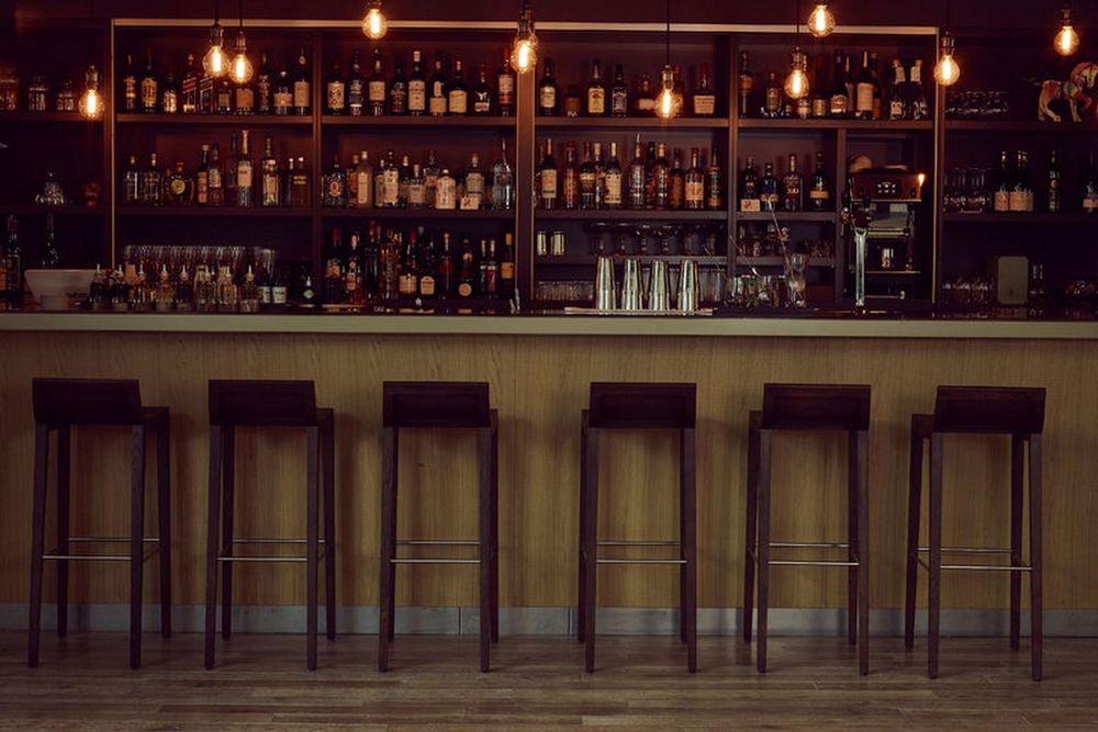 A row of tall bar stools before mirrored shelves of spirits at Le Bar du Parc, Fontainebleau