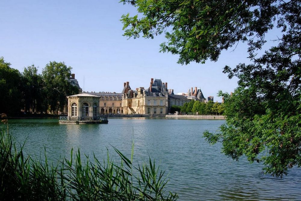 The Étang aux Carpes with its island pavilion and the château beyond, framed by reeds and trees