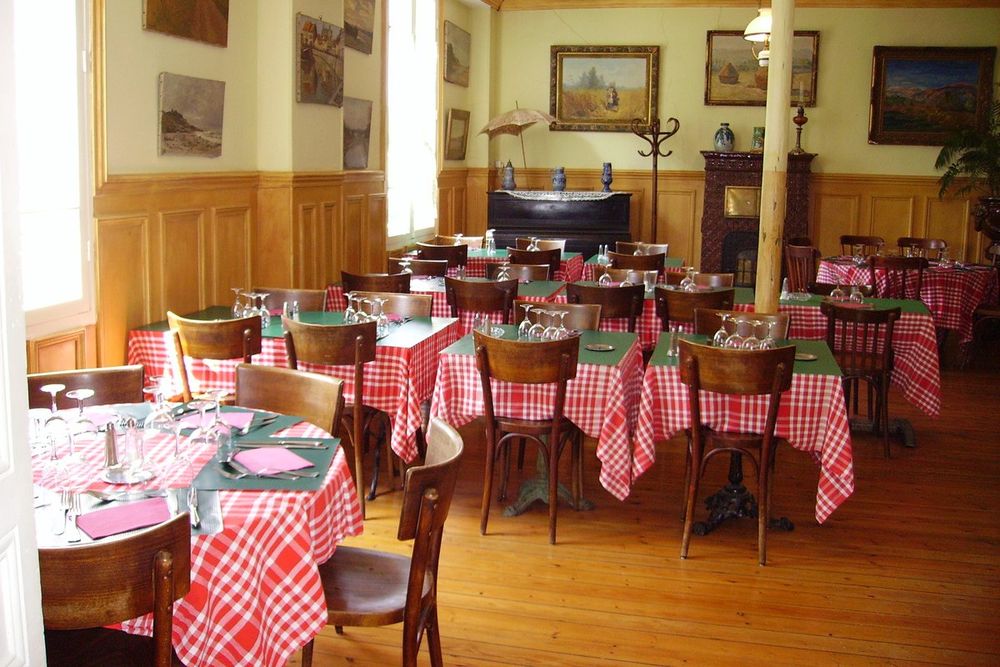 Gingham tablecloths and old paintings in the main dining room of the Ancien Hôtel Baudy