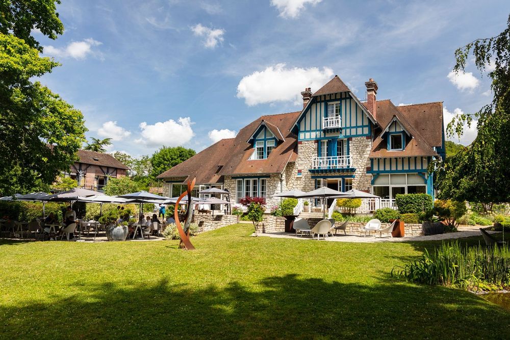 The half-timbered villa of Le Jardin des Plumes behind its lawn and terrace in Giverny