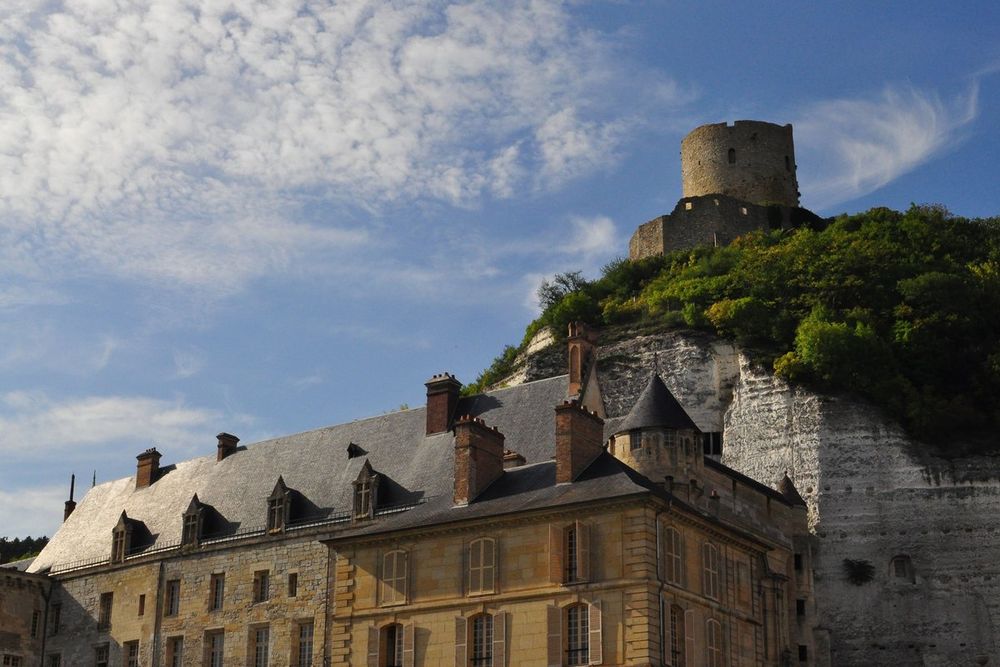 The round tower and carved façade of the Château de La Roche-Guyon against the chalk cliff