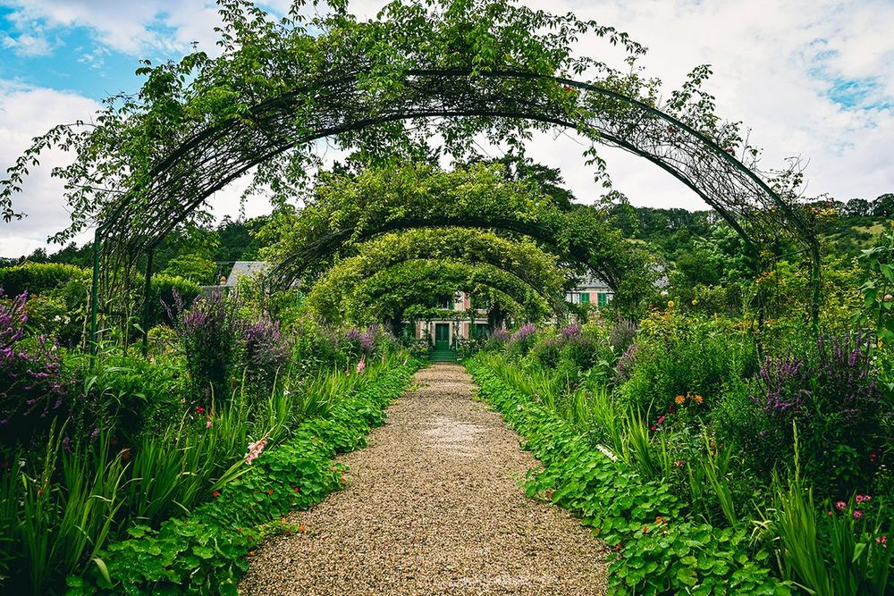 The Grande Allée under its iron arches in the Clos Normand of Monet's garden, with the house beyond