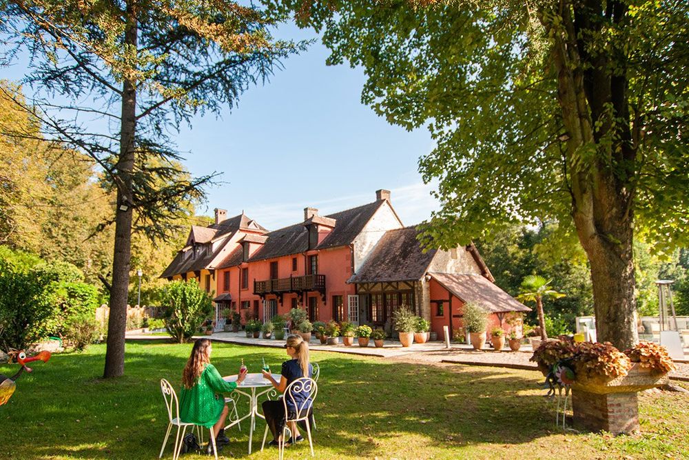 Guests at a garden table under the trees in front of the Moulin de Fourges