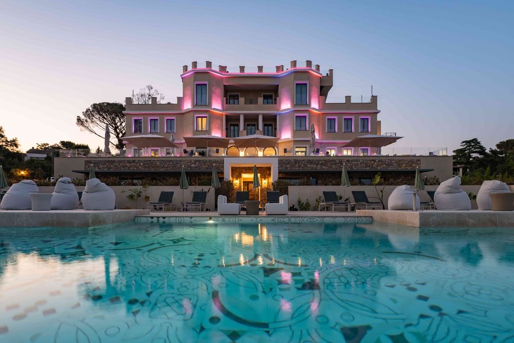 The pink Château Rose lit up at dusk behind its pool in Grimaud