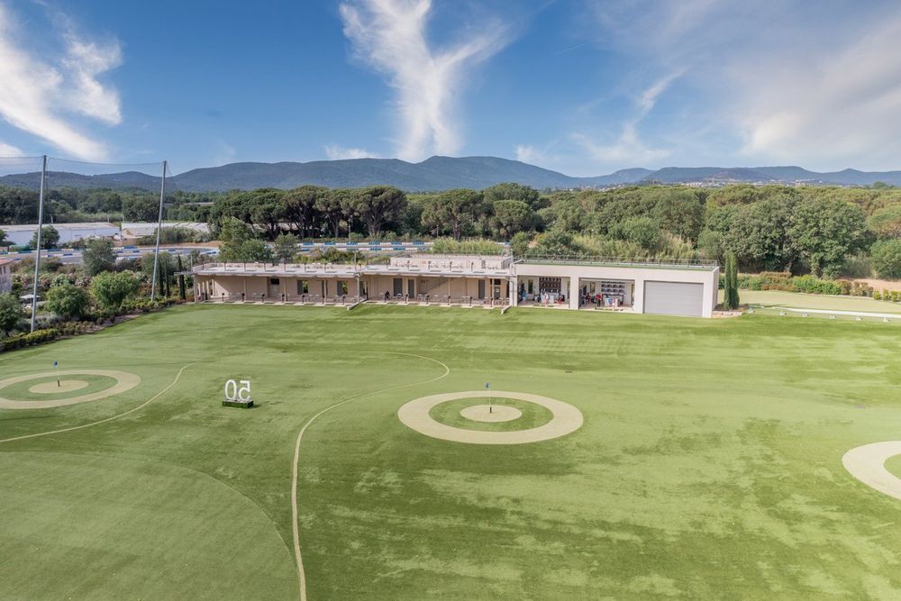 Target greens on the synthetic-turf practice range at Golf Up, the Maures hills behind
