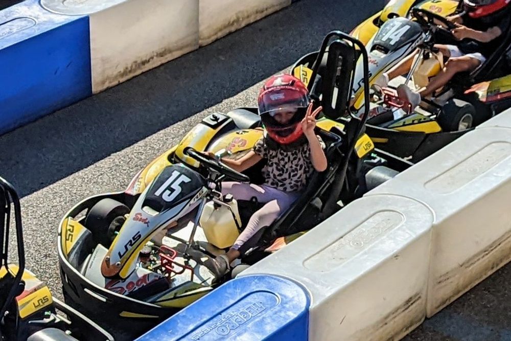 A child in a helmet at the wheel of a kart at Grimaud Karting Loisir