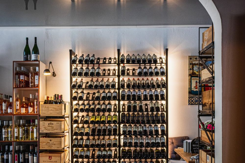 A wall of wine bottles on black racks in the cellar of L'Équille, Port Grimaud