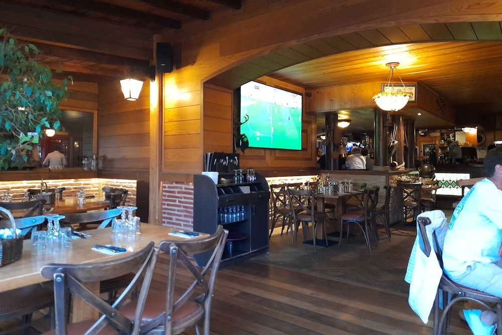Wooden tables, beams and a big screen inside Monroe's Pub in Port Grimaud